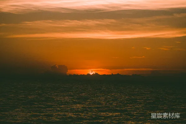 高清摄影 在多云的天气里，夕阳正缓缓落下，映照着海洋。
