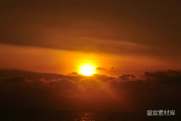 高清摄影 在多云的日子里，太阳正缓缓落下海洋之上。