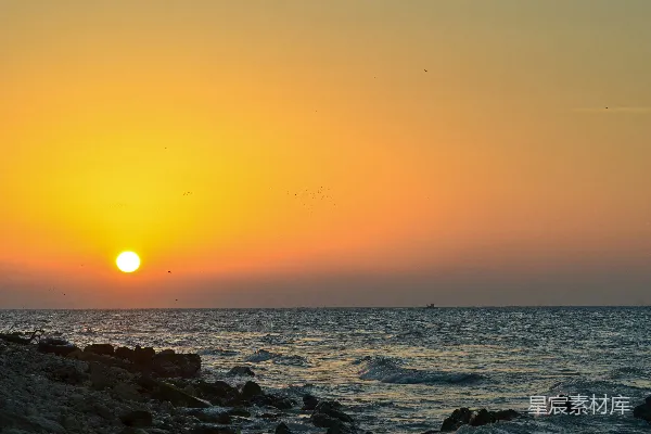 高清摄影 夕阳映照在海面上，远处有一艘船。