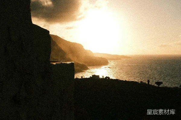 高清摄影 夕阳正落海平线上方，悬崖的轮廓在落日余晖中显得格外突出。