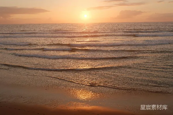 高清摄影 金色的夕阳照耀着平静的海浪和沙滩。