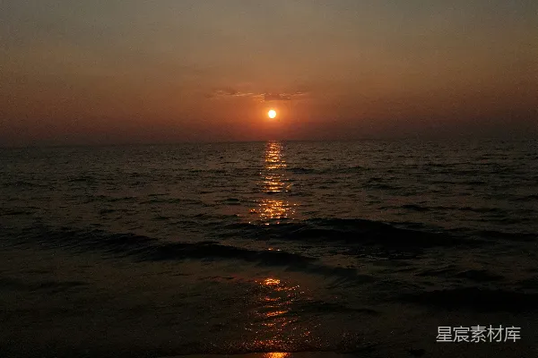 高清摄影 夕阳正缓缓沉落在海滩上的水面上。
