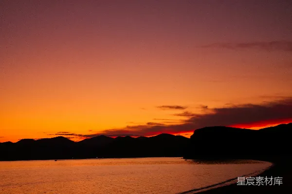 高清摄影 夕阳西下，水面上方有一片山脉。