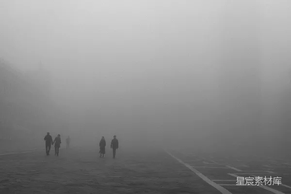 高清摄影 一群人在雾中沿着街道行走。