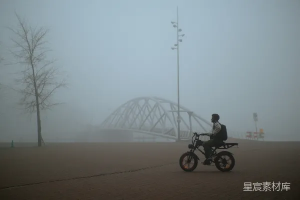 高清摄影 骑自行车的人在桥附近穿过雾气。
