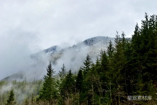 高清摄影 白天山脚下绿树成荫，白云缭绕。