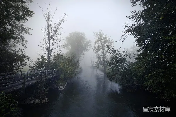 高清摄影 一条雾气缭绕的河流，前景中有一座木桥。