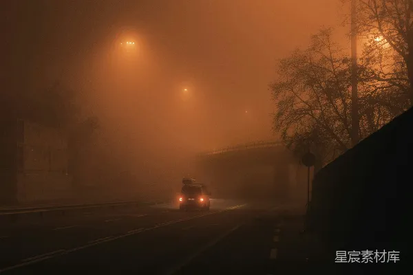 高清摄影 一辆汽车在夜间雾蒙蒙的街道上行驶。