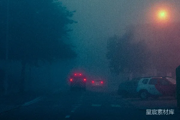 高清摄影 一条雾蒙蒙的街道，路边停着几辆汽车。