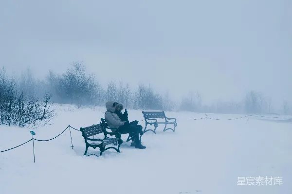 高清摄影 一个人独自坐在雪地里的公园长椅上。