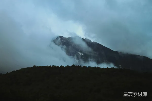 高清摄影 在多云的天气里，一座被雾气和云朵覆盖的山。