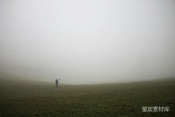 高清摄影 一个孤独的身影穿过一片雾气弥漫的草地。