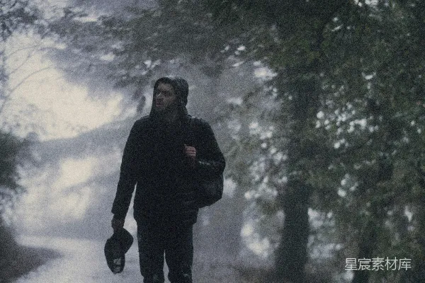 高清摄影 一个男人在雨中沿着马路行走。