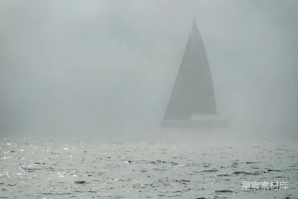 高清摄影 一艘帆船从浓雾中在水面上浮现。