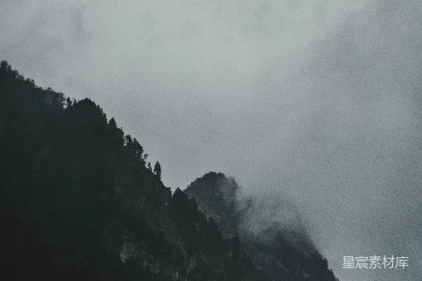 高清摄影 一座山被云雾和树木覆盖，在多云的天空下