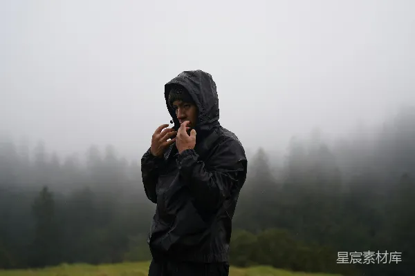 高清摄影 身穿黑色连帽夹克的人在浓密、雾气缭绕的森林中。