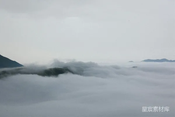 高清摄影 山峦在薄雾笼罩的天空下被云层覆盖。