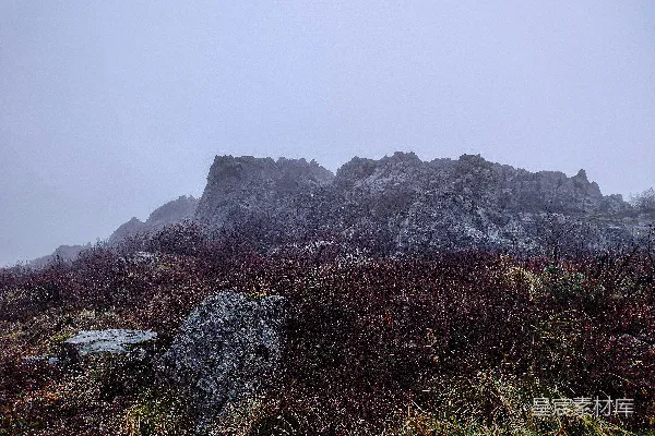 高清摄影 一座岩石山，前景中有草地和岩石。