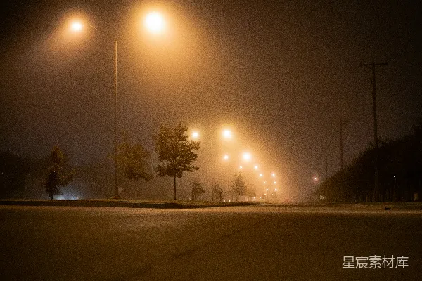 高清摄影 夜晚雾蒙蒙的街道上，路灯亮着。
