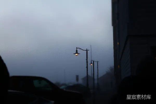 高清摄影 雾气笼罩下的街道上，路灯在清晨的微光中闪烁。