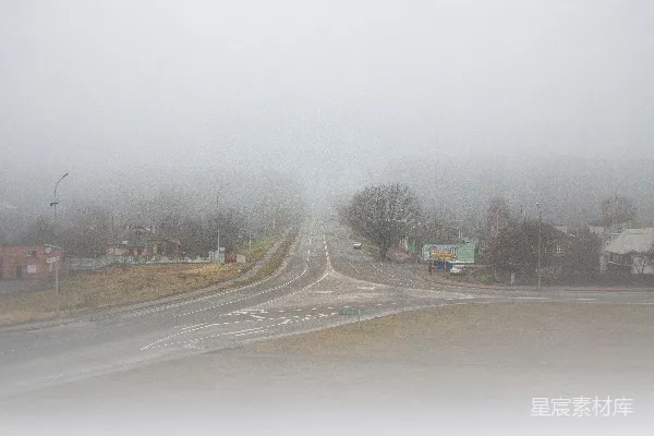 高清摄影 雾蒙蒙的道路交汇处，周围是建筑物和树木。