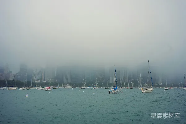 高清摄影 停泊在港湾中的帆船，远处是雾蒙蒙的城市天际线。