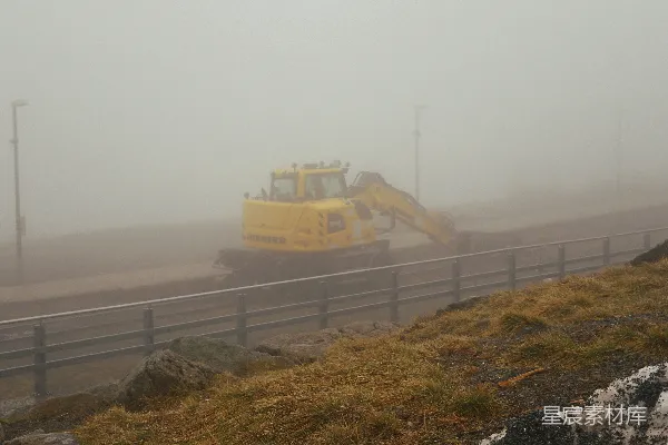高清摄影 一辆黄色的推土机在雾蒙蒙的天气里沿着道路行驶