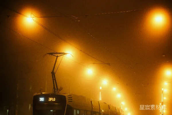 高清摄影 一辆火车在夜晚的雾气中沿着街道行驶