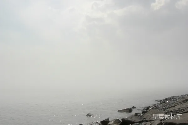 高清摄影 岩石海岸线在雾蒙蒙的天空下，海浪轻轻拍打。