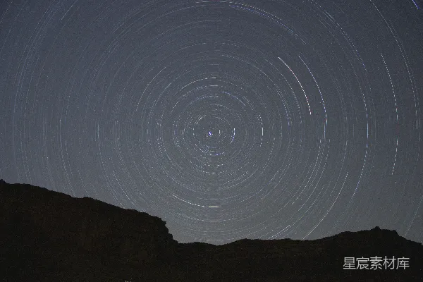 高清摄影 星星在夜空中穿过，形成围绕岩石剪影的同心圆。
