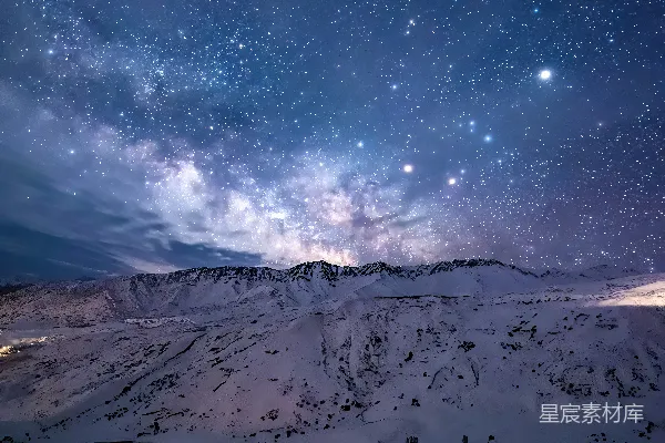 高清摄影 在积雪覆盖的山峰上方，夜空中布满了星星。
