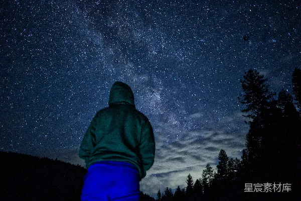 高清摄影 一个穿着绿色夹克的人仰望着夜空。