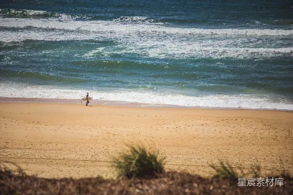 高清摄影 带着冲浪板的男人在海滩上行走