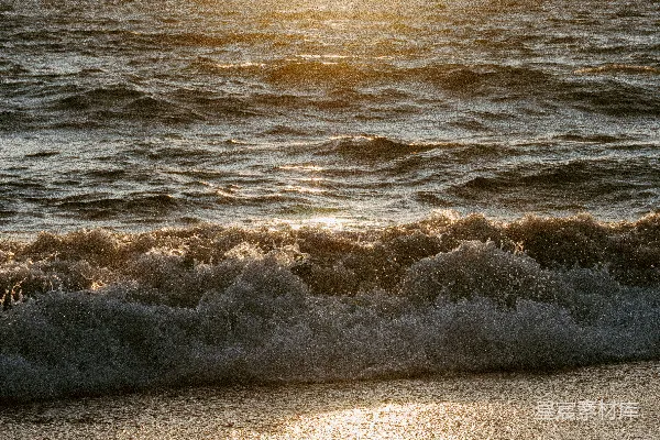 高清摄影 夕阳映照在海浪上，海浪拍打着沙滩。