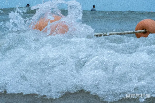 高清摄影 一个人在海浪中拖着一个橙色的浮标