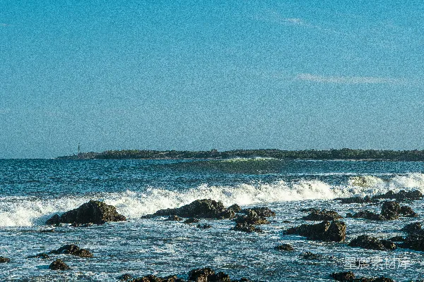 高清摄影 白天蓝天下的海浪拍打着岩石。