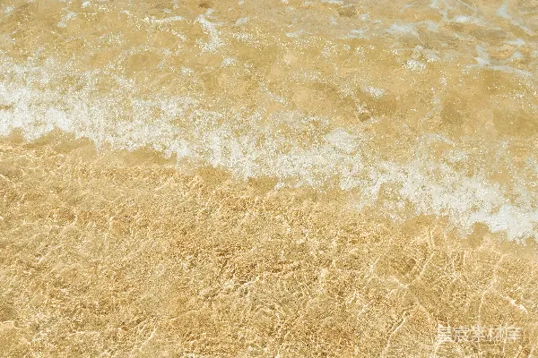 高清摄影 清澈的海水上覆盖着金色沙滩，小浪花轻轻拍打着。
