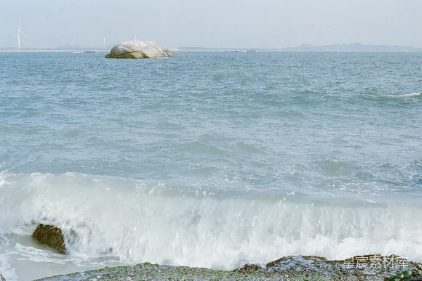 高清摄影 海浪拍打着岩石海岸，海中有一块大岩石。