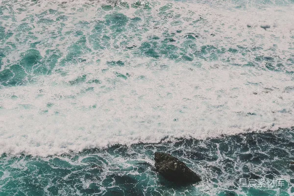 高清摄影 泡沫般的海浪拍打着暗色的礁石。