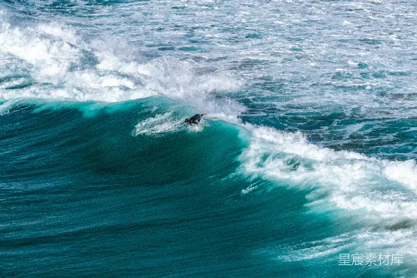 高清摄影 一个冲浪者在冲一个巨大的蓝绿色海浪。