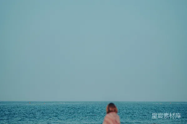 高清摄影 一个穿着白色连衣裙的女人在海滩上。