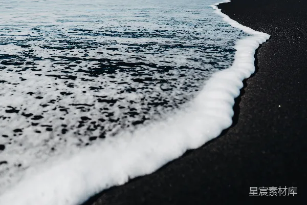 高清摄影 一片黑色的沙滩，海浪拍打着海岸。
