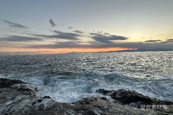 高清摄影 夕阳洒在海浪之上，海岸线布满岩石。