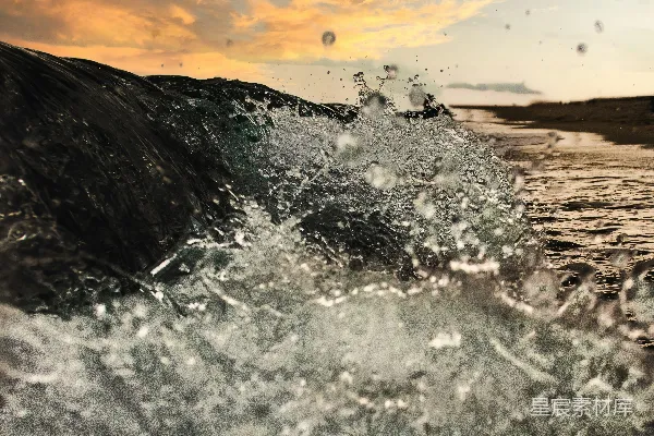 高清摄影 在日落时分，一个人在海浪中冲浪。