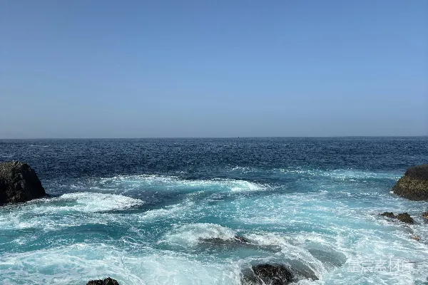 高清摄影 波浪在清澈的蓝天下拍打着岩石。