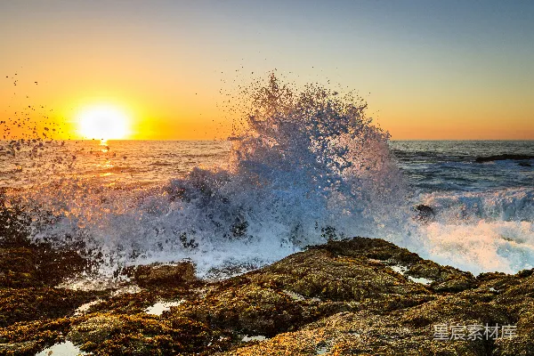高清摄影 夕阳正沉落在海洋上，海浪重重地拍打着岸边。