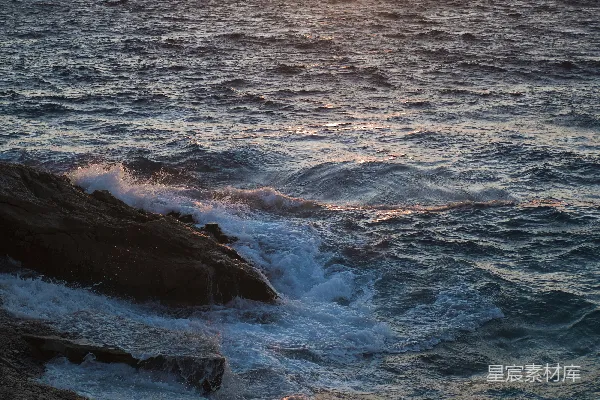 高清摄影 夕阳下，海浪拍打着岩石。