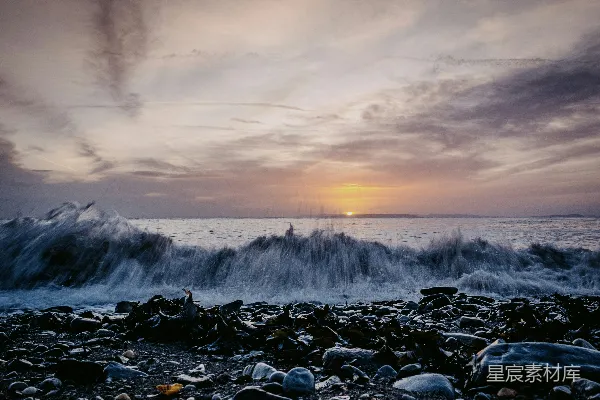 高清摄影 夕阳正落下海面，波浪拍打着沙滩。