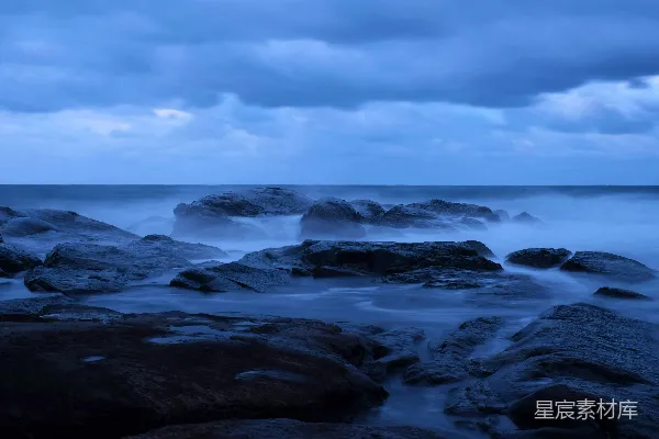 高清摄影 白天，白云下的蓝天中，海浪拍打着岩石。
