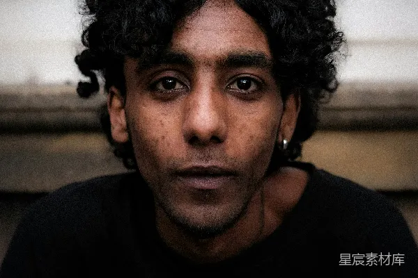 高清摄影 一个头发卷曲的男子正在看着镜头。
